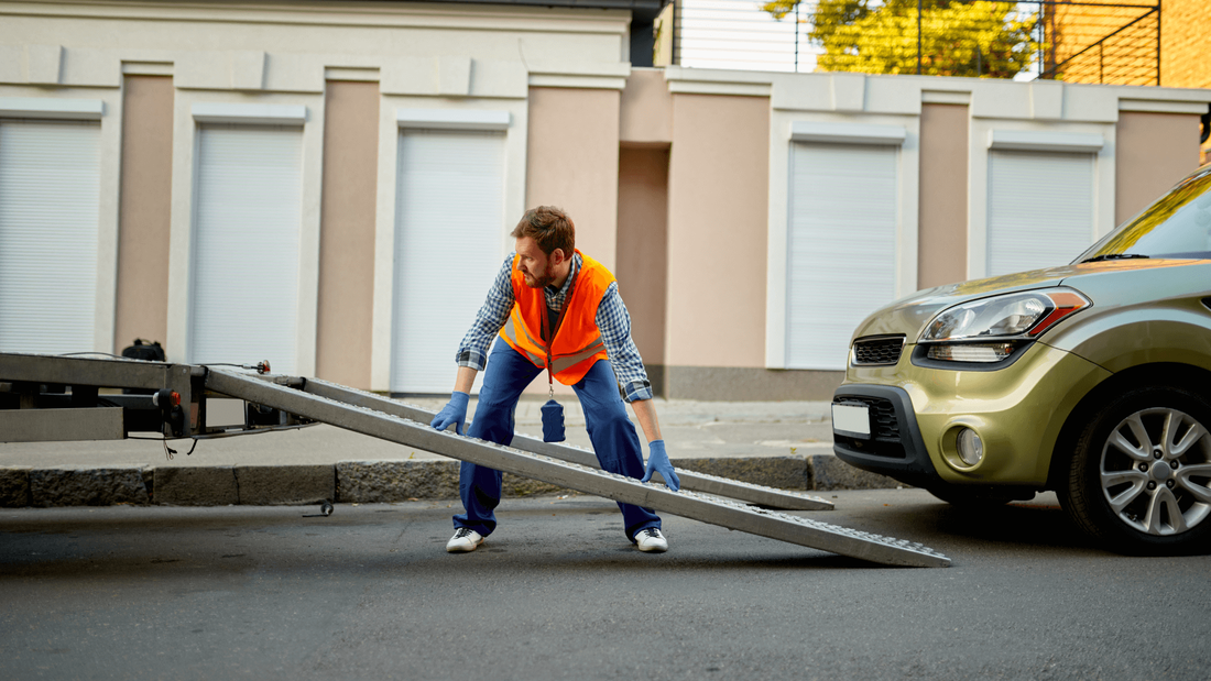 Man in orange suit helping to tow a car out of MI